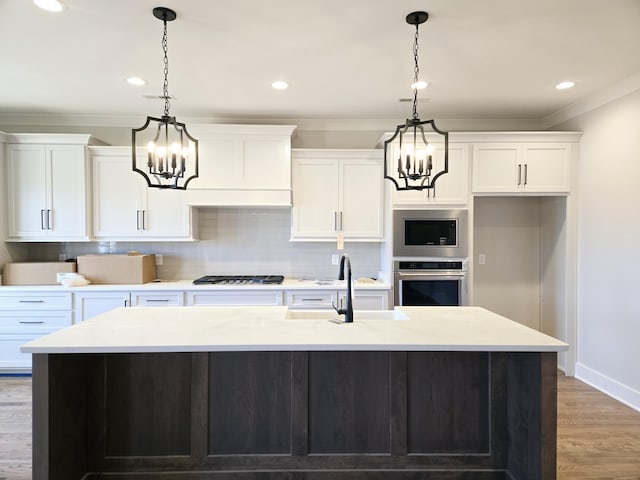 kitchen with decorative light fixtures, stainless steel appliances, and a center island with sink