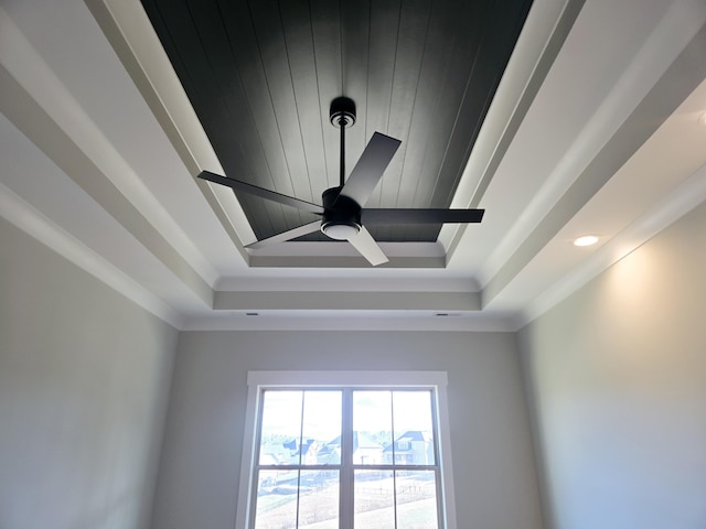 interior details with ornamental molding, ceiling fan, and a tray ceiling