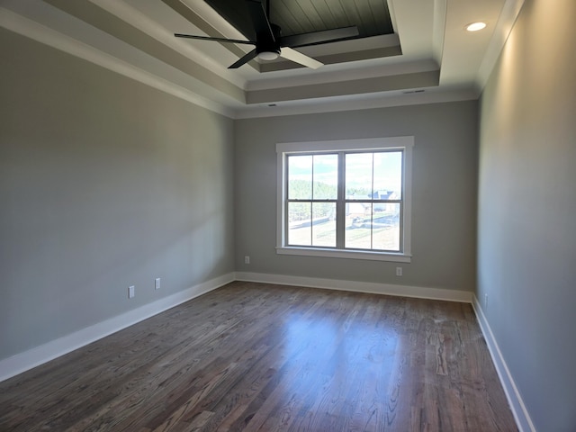 spare room featuring dark hardwood / wood-style floors, ceiling fan, ornamental molding, and a tray ceiling