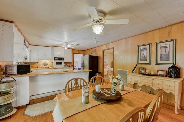 dining room with ceiling fan, light wood-type flooring, and ornamental molding