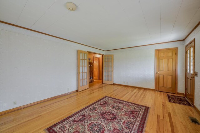 empty room featuring ornamental molding, french doors, and light hardwood / wood-style floors