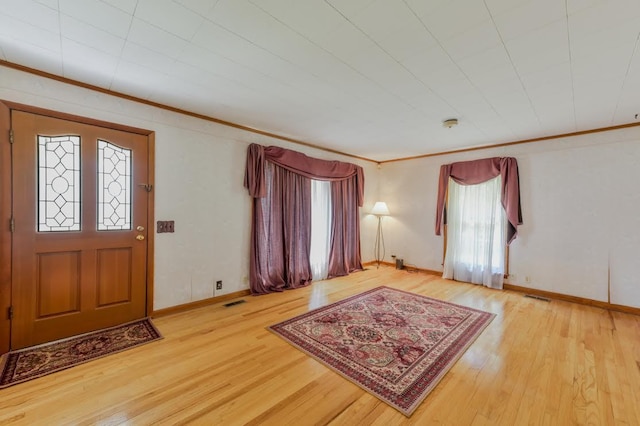 entryway with visible vents, light wood-style floors, and ornamental molding