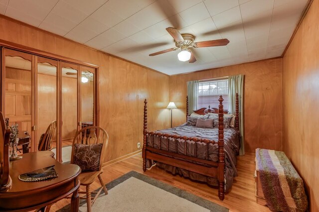 bedroom featuring ceiling fan, wooden walls, and light hardwood / wood-style flooring