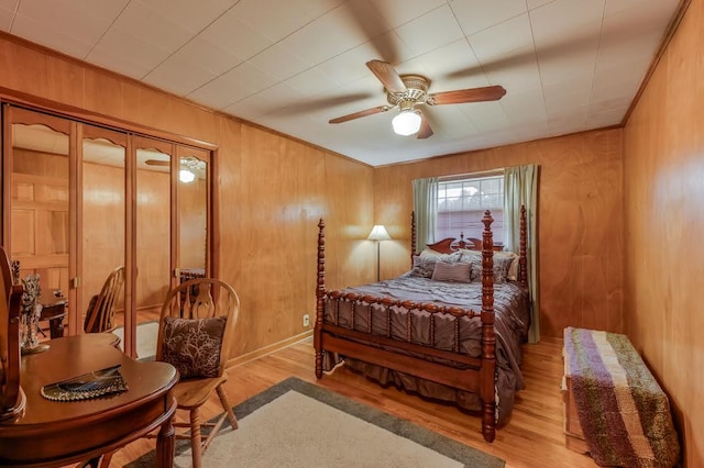 bedroom featuring ceiling fan, light wood-style flooring, wooden walls, and ornamental molding