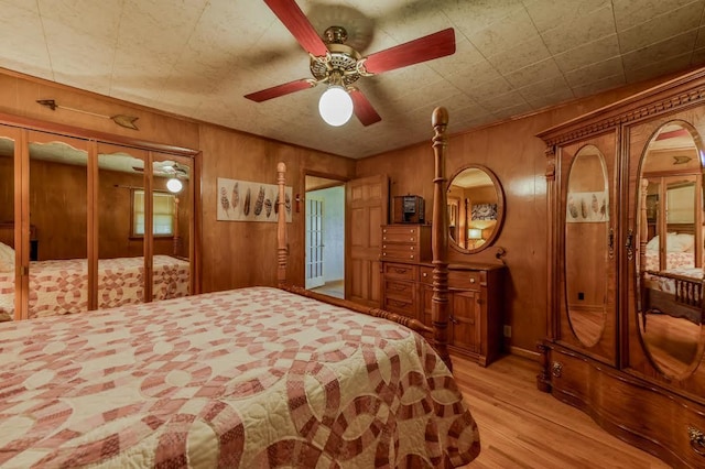 bedroom featuring light wood-type flooring, wooden walls, a ceiling fan, and french doors