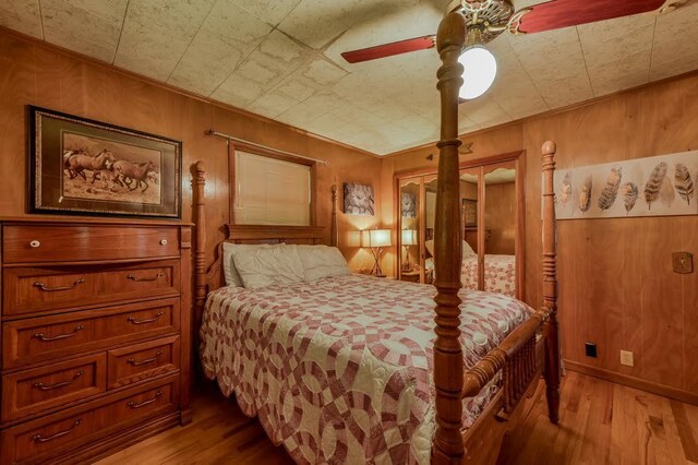 bedroom featuring ceiling fan, wooden walls, and light hardwood / wood-style floors