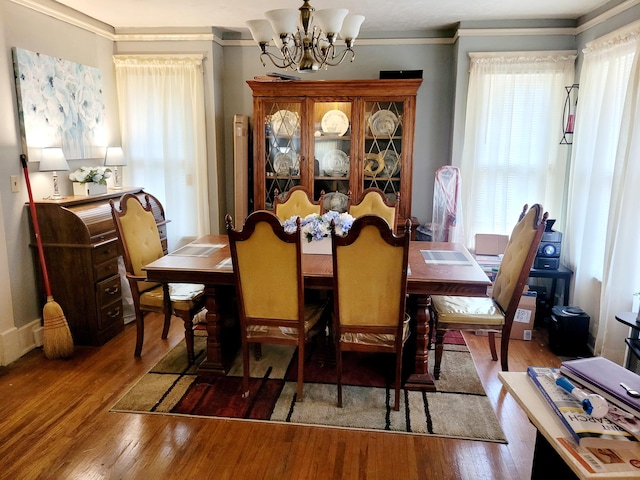 dining room featuring wood-type flooring, ornamental molding, and a chandelier