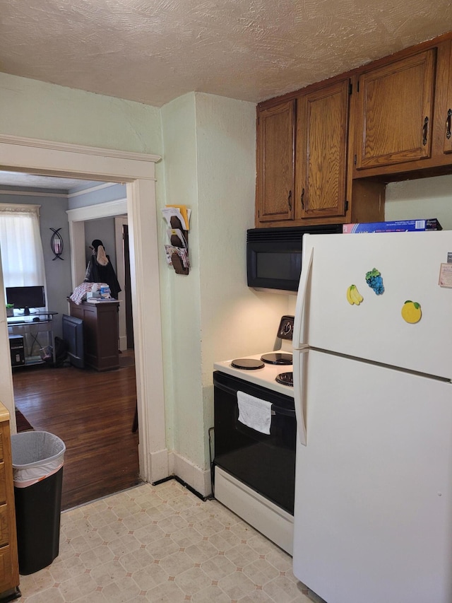 kitchen featuring a textured ceiling, light wood-type flooring, and white appliances