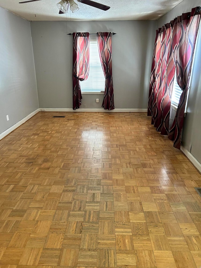 unfurnished room with ceiling fan, a textured ceiling, and light parquet floors