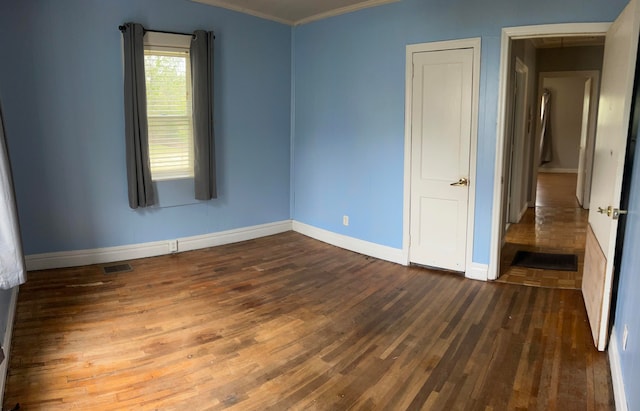 unfurnished bedroom with crown molding and dark hardwood / wood-style floors