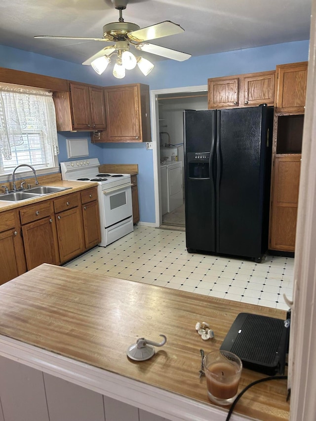 kitchen featuring black refrigerator with ice dispenser, ceiling fan, washer and dryer, white electric stove, and sink