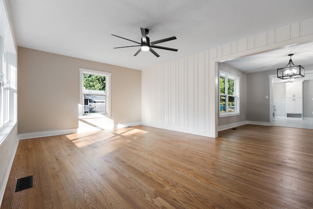 unfurnished living room with wood-type flooring and ceiling fan with notable chandelier