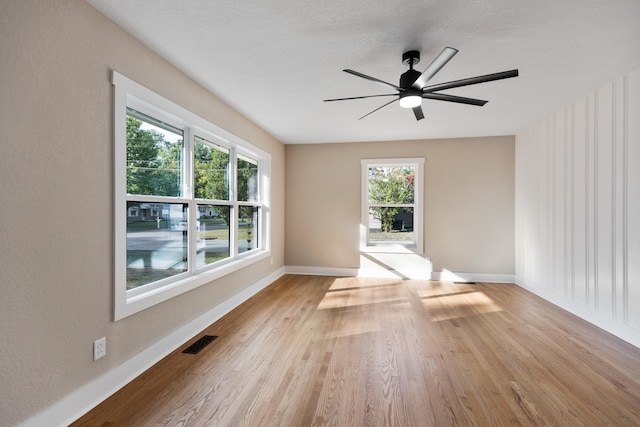 unfurnished room featuring ceiling fan, light hardwood / wood-style floors, and a healthy amount of sunlight