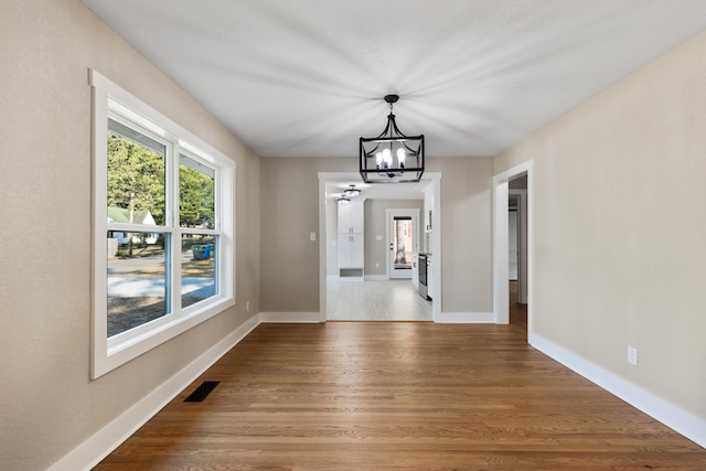 unfurnished dining area with a chandelier and light hardwood / wood-style floors