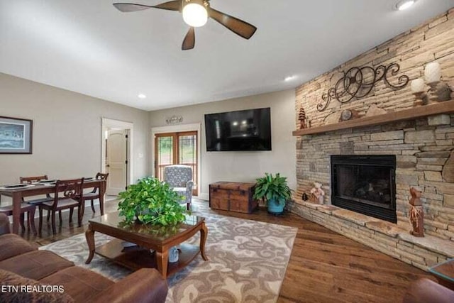 living room with a fireplace, ceiling fan, and wood finished floors