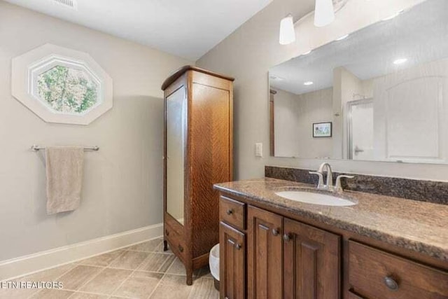 bathroom featuring vanity, an enclosed shower, baseboards, and tile patterned flooring