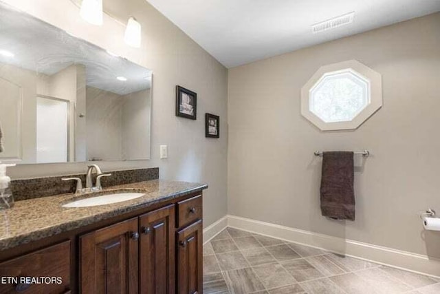 full bathroom with a shower with shower door, visible vents, baseboards, and vanity