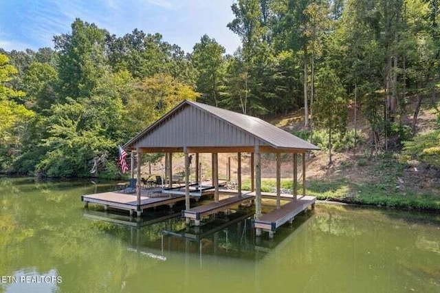 view of dock with a forest view and a water view