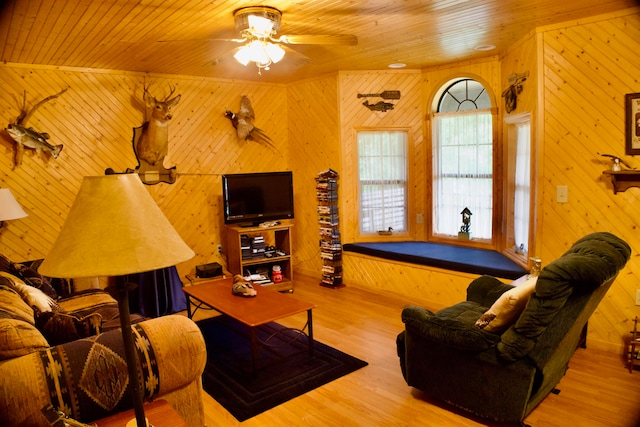 living room with ceiling fan, light wood-type flooring, wooden ceiling, and wooden walls