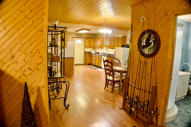 interior space with light wood-type flooring, a chandelier, wood walls, and wooden ceiling