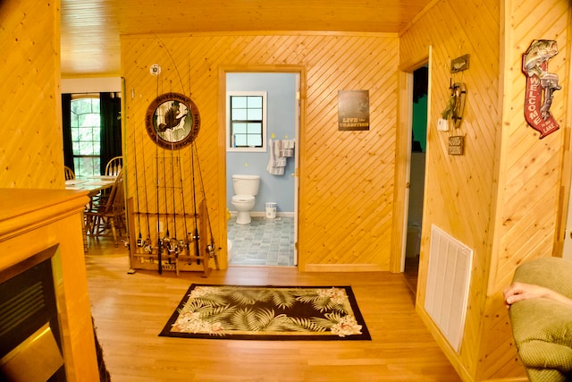 interior space featuring crown molding, wooden walls, and light hardwood / wood-style floors