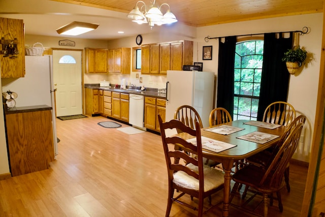 dining area featuring light wood-type flooring, sink, and a notable chandelier