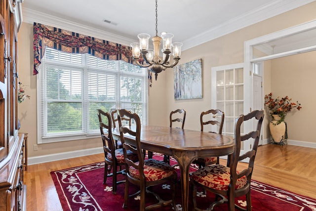 dining area featuring ornamental molding, an inviting chandelier, and light wood-type flooring