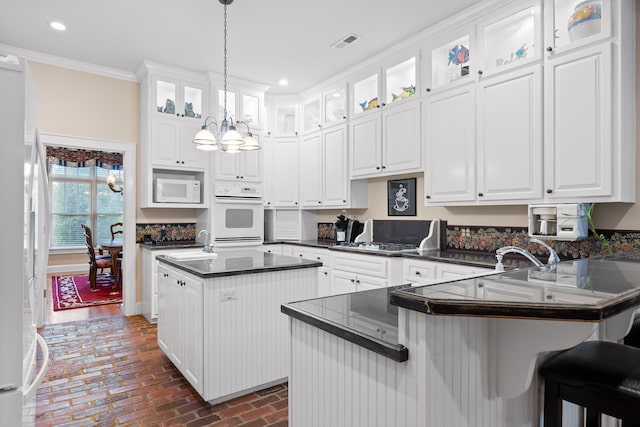 kitchen with white cabinetry, white appliances, a chandelier, decorative light fixtures, and kitchen peninsula