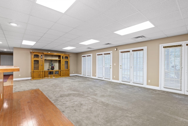 unfurnished living room with hardwood / wood-style flooring and a drop ceiling