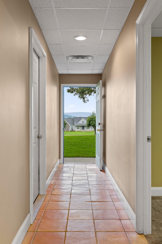 corridor featuring a paneled ceiling and light tile patterned floors