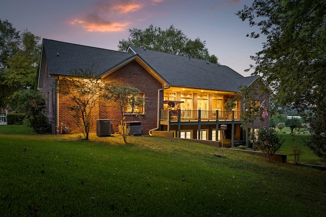 back house at dusk featuring a lawn