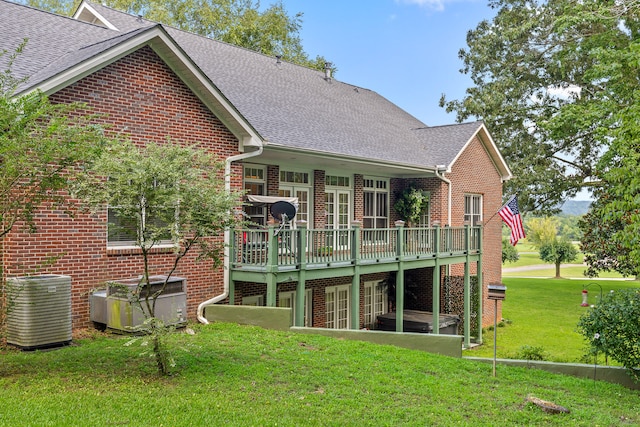 rear view of property with cooling unit, a yard, and a deck