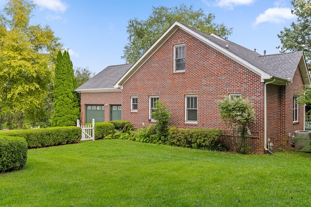 view of front of property featuring a front lawn, a garage, and central AC