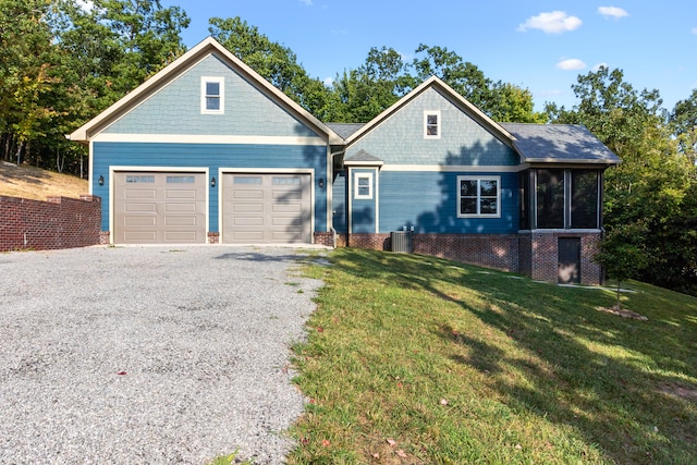 view of front facade with a garage, a front yard, a sunroom, and cooling unit