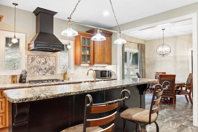 kitchen with tasteful backsplash, appliances with stainless steel finishes, premium range hood, and light stone countertops