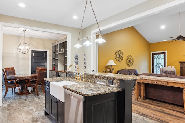 kitchen featuring ceiling fan with notable chandelier, dishwasher, sink, lofted ceiling, and stone counters