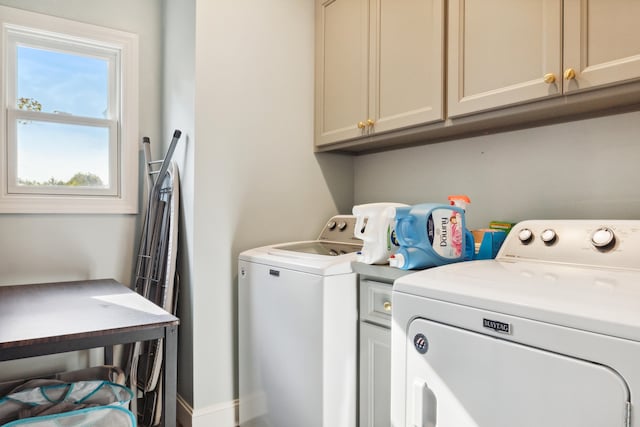 clothes washing area with washing machine and clothes dryer and cabinets