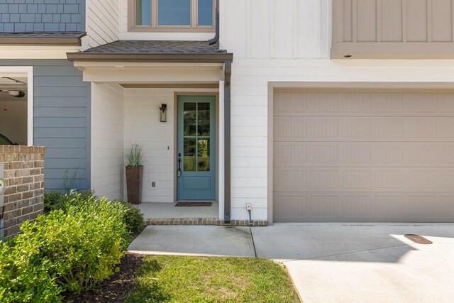 entrance to property with concrete driveway, board and batten siding, and a shingled roof