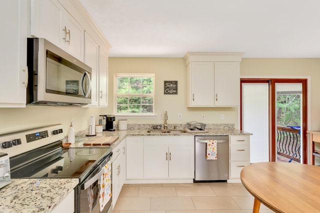 kitchen featuring appliances with stainless steel finishes, light tile patterned flooring, sink, and white cabinets