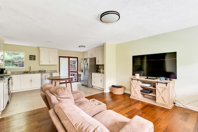 living room with a textured ceiling, light hardwood / wood-style flooring, and sink