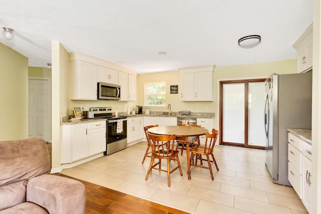 kitchen with sink, light stone countertops, appliances with stainless steel finishes, and light tile patterned flooring