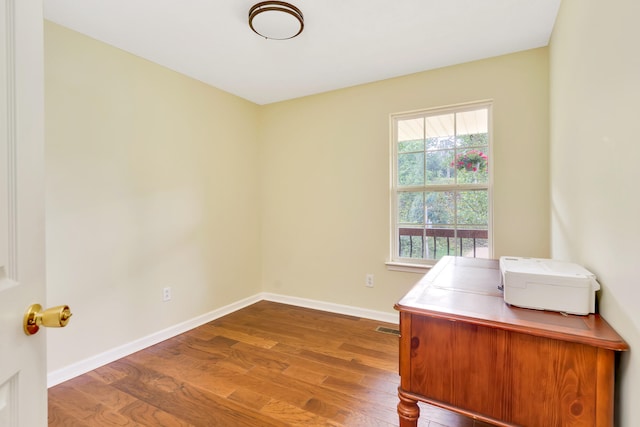 unfurnished office featuring hardwood / wood-style flooring and a healthy amount of sunlight