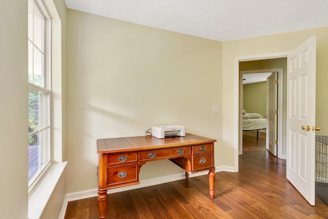 corridor with a wealth of natural light and dark hardwood / wood-style floors