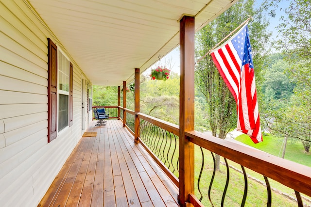 wooden terrace featuring a yard and covered porch