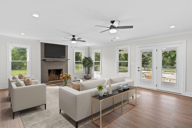 living room featuring a fireplace, crown molding, wood-type flooring, and ceiling fan