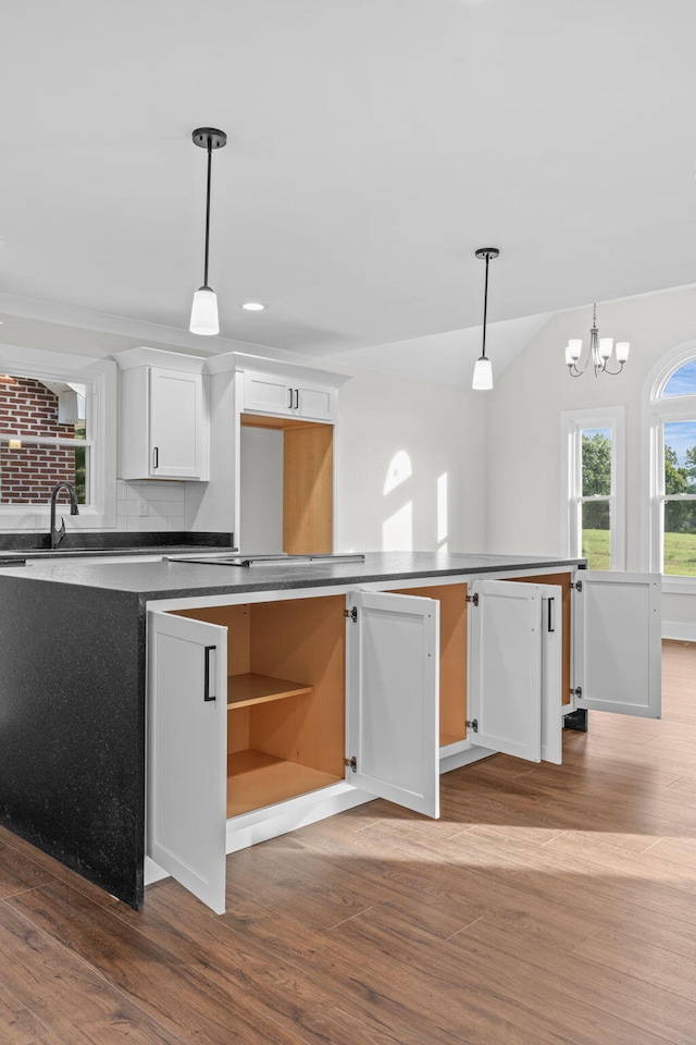 kitchen featuring decorative light fixtures, hardwood / wood-style floors, tasteful backsplash, a chandelier, and white cabinets