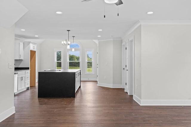 kitchen featuring ceiling fan with notable chandelier, dark wood-type flooring, crown molding, and a kitchen island