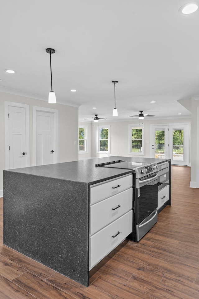 kitchen with stainless steel range with electric stovetop, ornamental molding, white cabinetry, dark hardwood / wood-style flooring, and ceiling fan