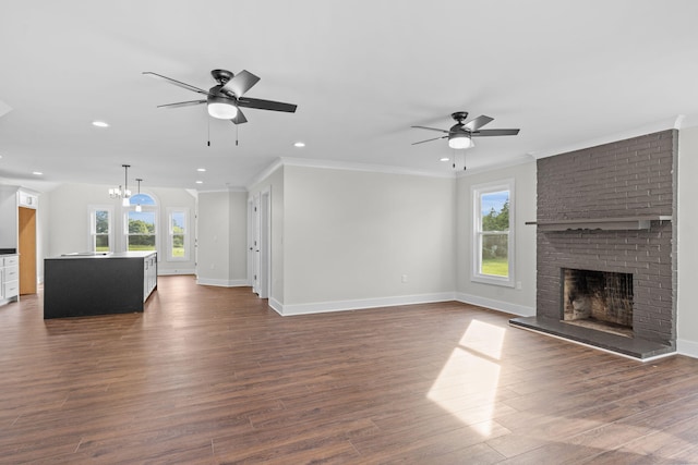 unfurnished living room with dark wood-type flooring, ceiling fan with notable chandelier, and a fireplace