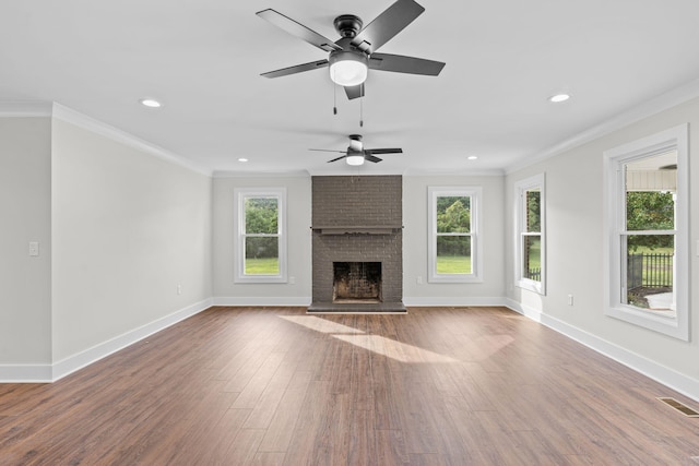 unfurnished living room featuring ceiling fan, hardwood / wood-style flooring, ornamental molding, and a brick fireplace